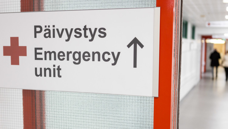 Sairaalan sisätiloissa oleva liukuovi ja siinä kyltti jossa punainen risti ja teksti Päivystys - Emergency unit