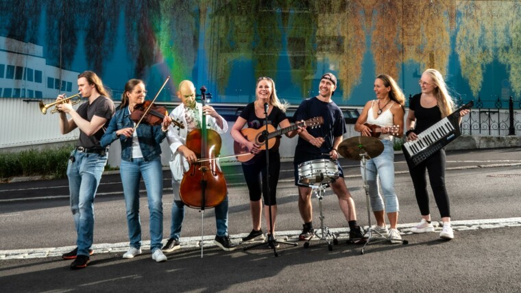Kuvituskuva. Kuvassa seitsemän henkilöä soittamassa eri instrumentteja kuumalla kesäkadulla.