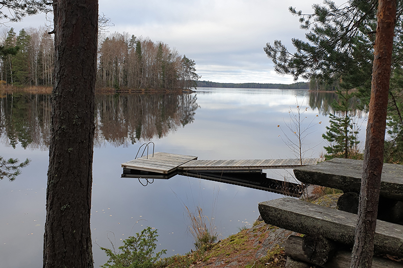 Kuvituskuva kallioisesta rannasta, josta laituri viettää järveen.