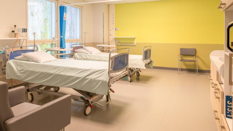 Mikkelin keskussairaalan synnytysosaston perhehuone, jossa kaksi sairaalasänkyä, isot ikkunat, nojatuoli ja keittiövarustus.