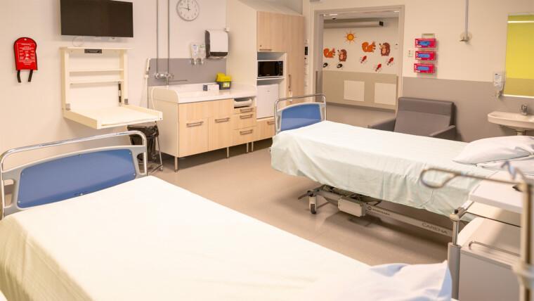 Mikkelin keskussairaalan synnytysosaston perhehuone, jossa kaksi sairaalasänkyä, nojatuoli, keittiövarustus ja vauvanhoitopaikka.