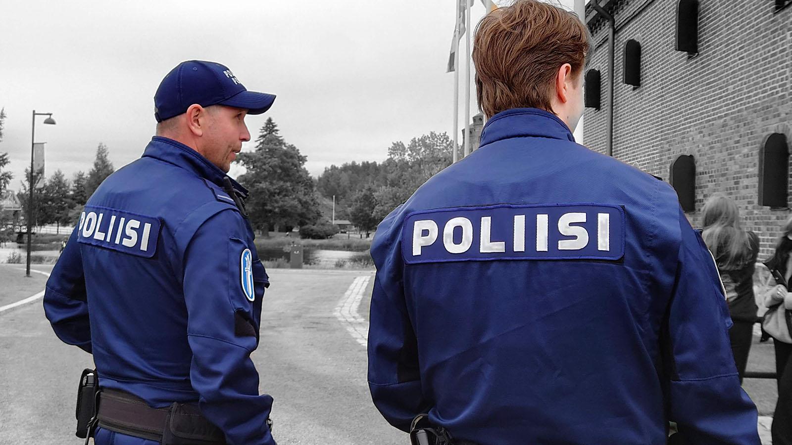 Kuvituskuva: kaksi poliisia siniset univormut päällään. Univormun selkämyksessä lukee POLIISI.
