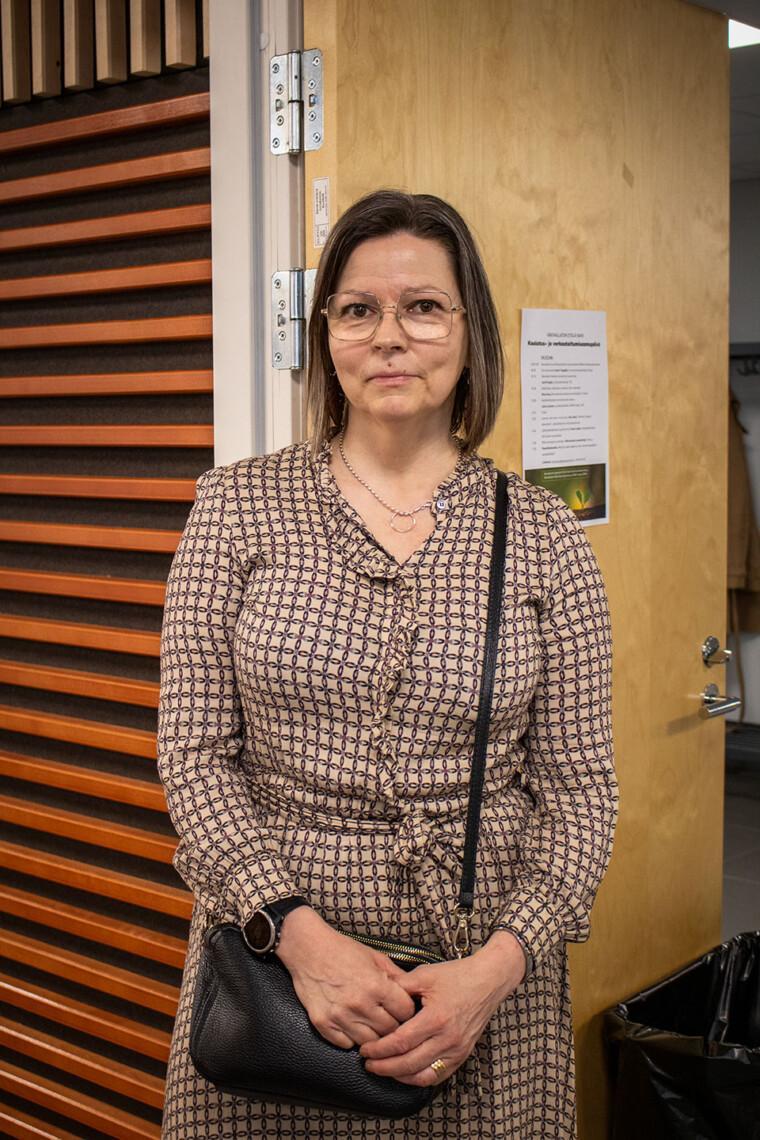 Jonna Laitonen seisoo auditorion edessä ja katsoo kameraan.
