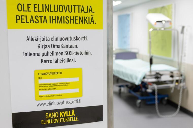 Keltamusta elinluovutuskortin infojuliste Mikkelin keskussairaalan teho- ja valvontaosaston käytävän seinällä, taustalla potilassänky